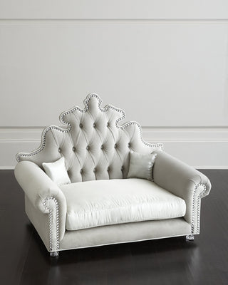 Haute House Isabella pet bed in light grey upholstery on a hardwood frame, with jeweled nailhead trim and two square pillows. photograph: Haute House for Neiman Marcus