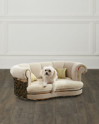 Haute House Dorina peacock pet bed in cream upholstery with two velvet pillows and a small white dog resting on the cushion. photograph: Haute House for Neiman Marcus